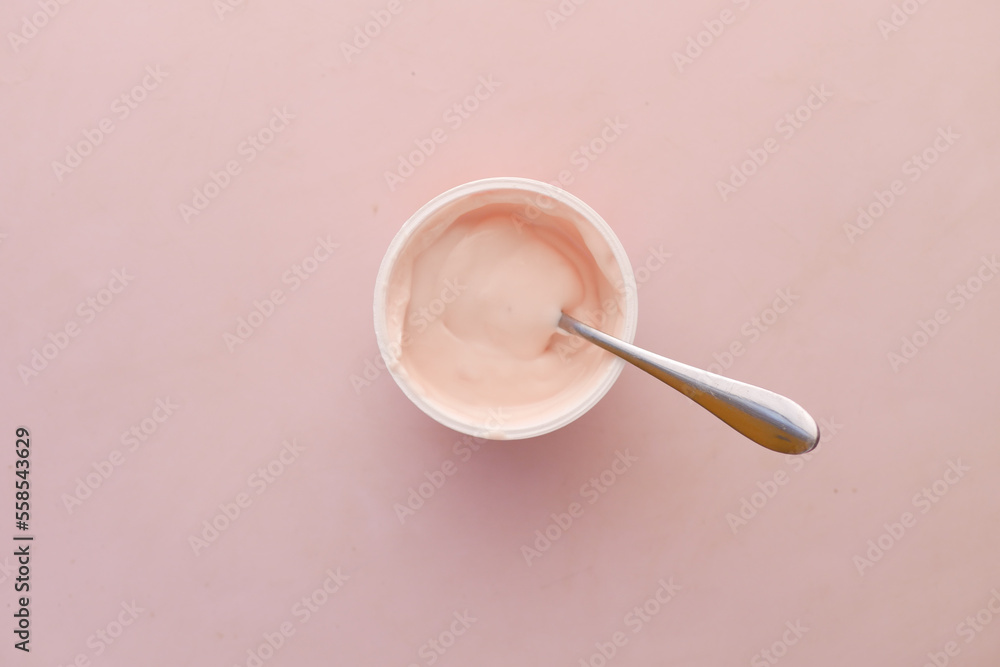 fresh yogurt in a plastic container and spoon on table fresh yogurt in a plastic container and spoon on table