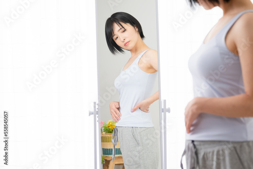 鏡でウェストをチェックする若い女性 ダイエットイメージ