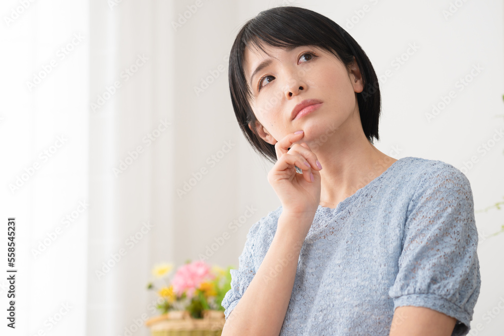 部屋で考え事をする若い女性