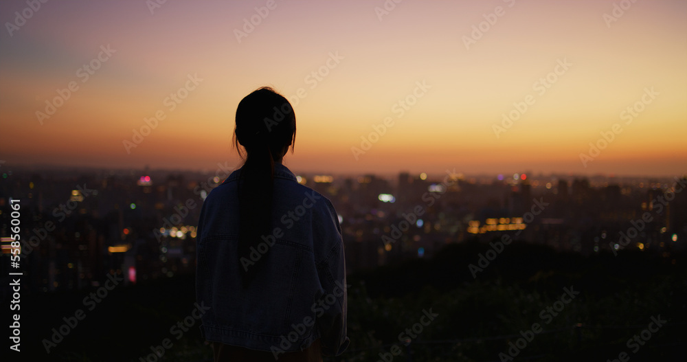 Fototapeta premium Silhouette of woman look at the city under sunset