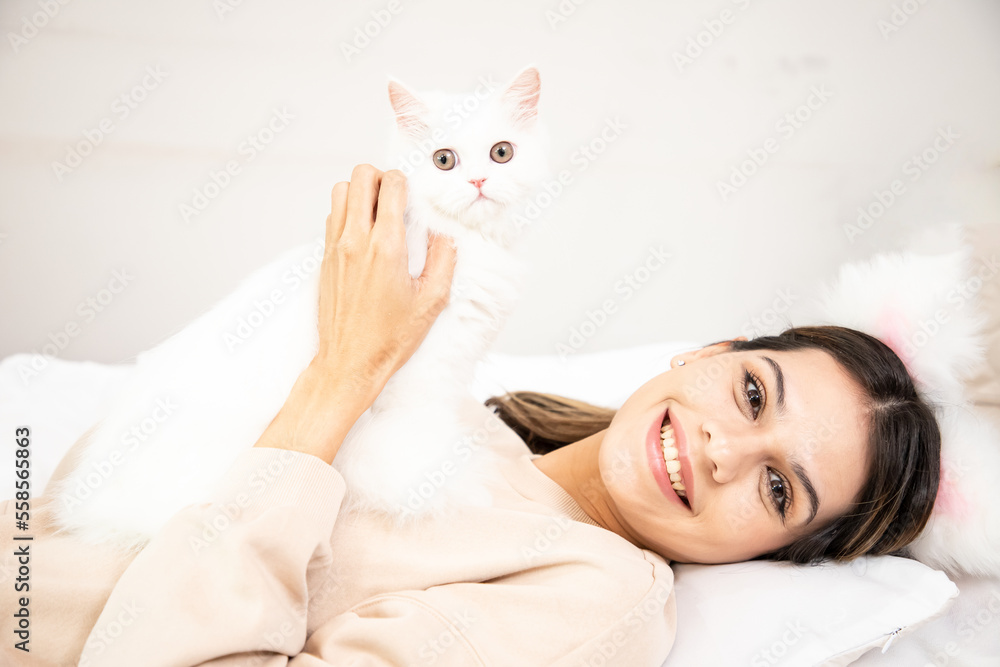 Portrait of the beautiful little girl with brunette loose hair the hugging her white cat. Girl is laying with her cat Portrait of the beautiful little girl with brunette loose hair the hugging her white cat. Girl is laying with her cat