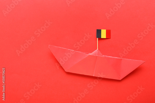 Paper ship and small flag of Belgium on red background photo