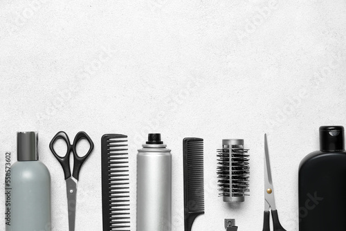Hair care products with brushes and scissors on light background