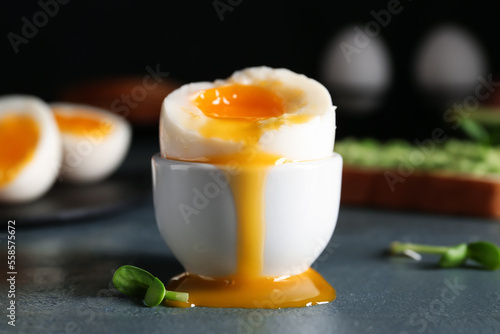 Foto Holder with soft boiled egg on wooden table