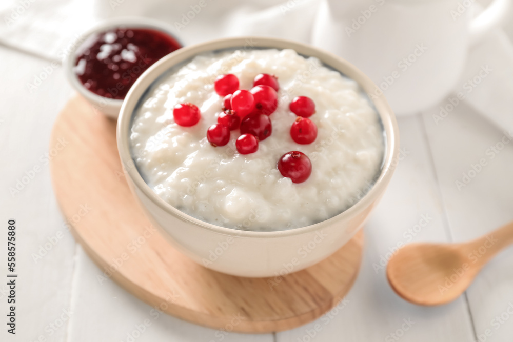 Bowl with delicious rice pudding, cranberry and jam on white wooden table Bowl with delicious rice pudding, cranberry and jam on white wooden table