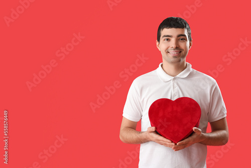 Young man with gift on red ...