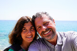 cheerful happy tourist couple middle aged taking selfie in vacation on coast beach sea