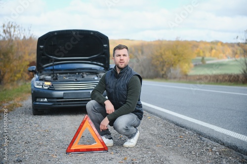 Handsome young man with his car broken down by the roadside © Serhii