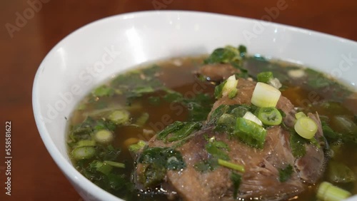 Traditional Thai duck leg and mushroom soup Guay Teaw Ped Toon, Roasted duck leg in savory broth filled with herbs and mushrooms, close up slider 4K photo