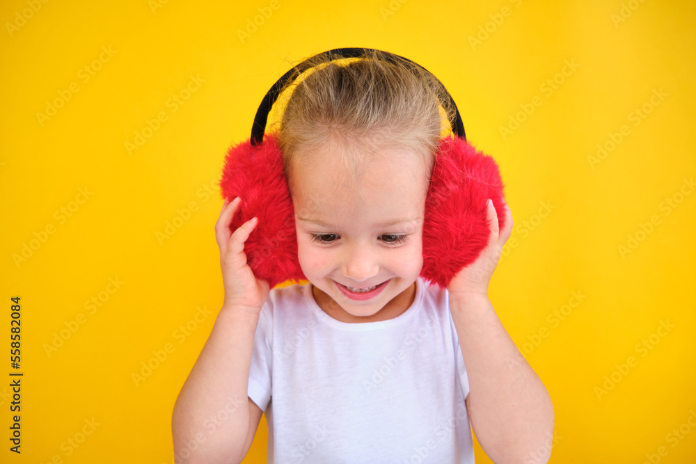happy Cute smiling little girl stylish winter earmuffs light yellow background happy Cute smiling little girl stylish winter earmuffs light yellow background