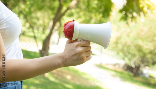 Caucasian woman holding megaphone at outdoor.