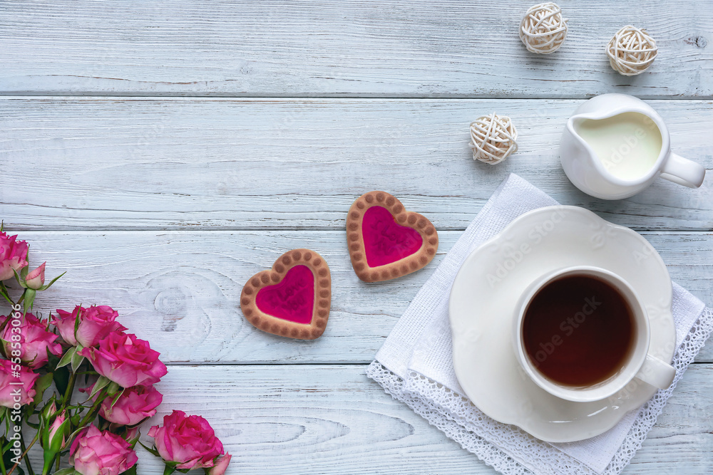Homemade cookies in the form of hearts with pink jam with a cup of tea on wooden light blue boards with roses. The concept of Valentine's Day. Flat lay. Homemade cookies in the form of hearts with pink jam with a cup of tea on wooden light blue boards with roses. The concept of Valentine's Day. Flat lay.