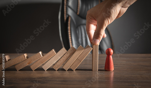 Male hand stopping wooden blocks from falling on human figure.