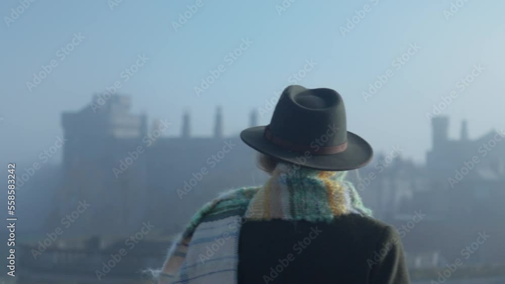 Woman watching medieval castle from rooftop in misty day Woman watching medieval castle from rooftop in misty day