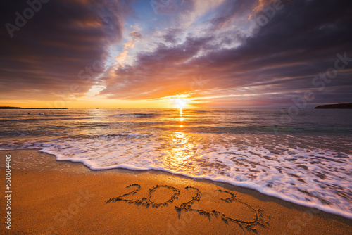 Happy New Year 2023 concept, lettering on the beach. Written text on the sea beach at sunrise.