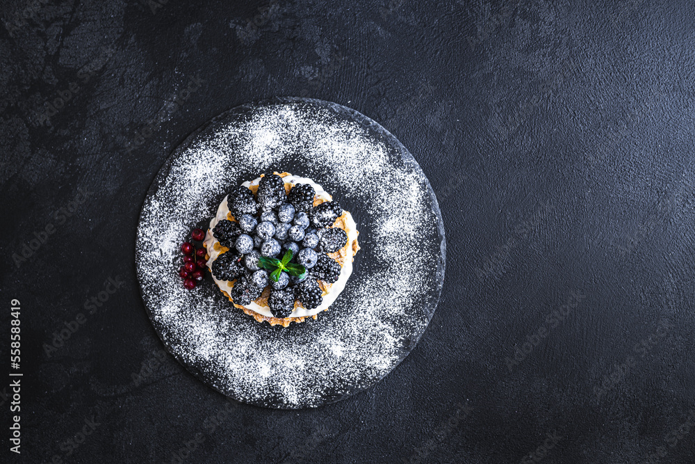 Top down view of homemade waffles with blueberries and blackberries on the top on stone plate 