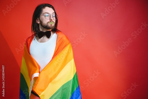 Gay man hold rainbow striped flag isolated on colored background studio portrait. People lifestyle fashion lgbtq concept