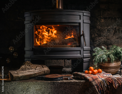 Fotografiet burning fireplace in a dark room with tangerines, plaid