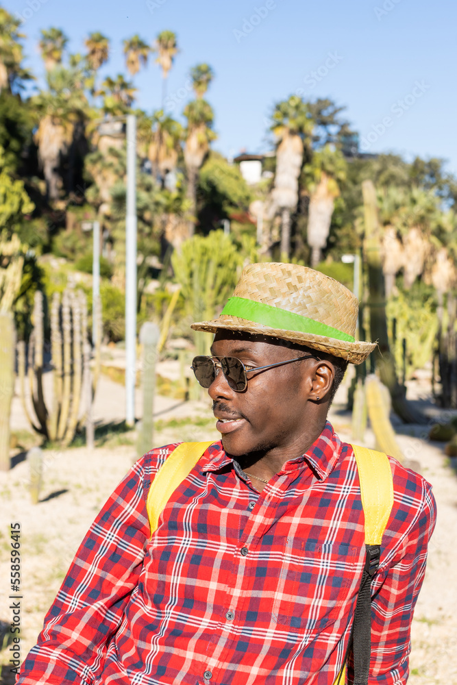 Happy African man in red shirt and hat in a garden in Barcelona (Spain).