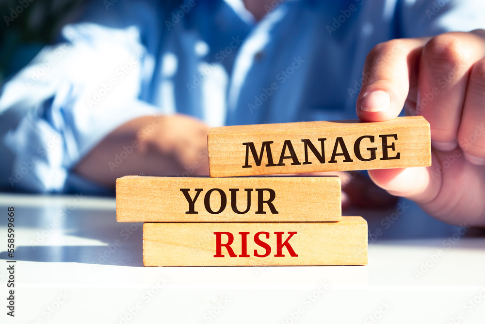 Closeup on businessman holding a wooden blocks with text 'Manage your risk', business concept Closeup on businessman holding a wooden blocks with text 'Manage your risk', business concept