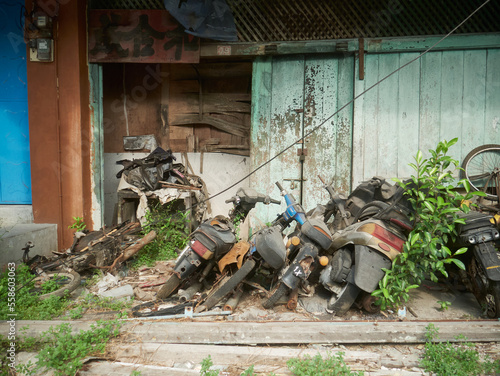 A heap of rusty motorcycles left in front of an old wooden shop.