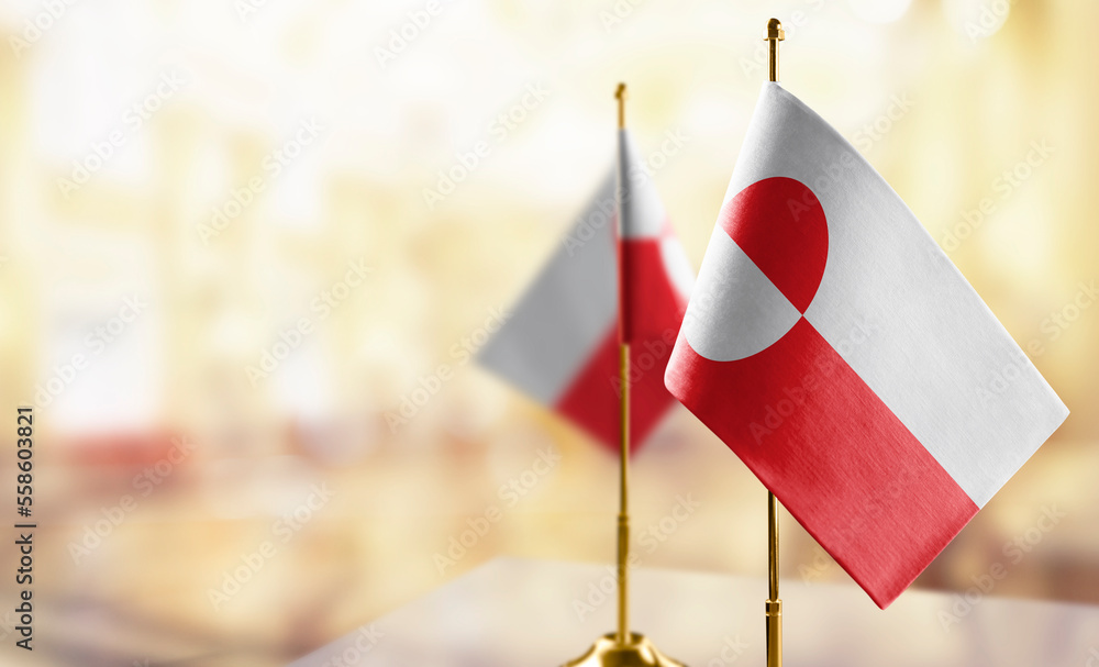 Small flags of the Greenland on an abstract blurry background