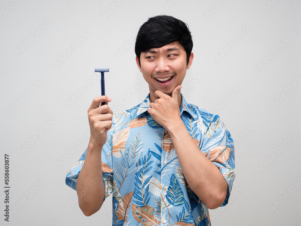 Positive asian man looking at shaving in his hand and thinking something isolated Positive asian man looking at shaving in his hand and thinking something isolated