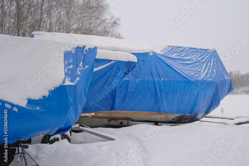 Yacht, boat, ship on the shore under a canopy awning in the snow