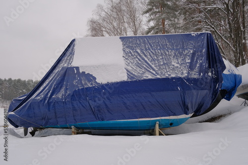 Yacht, boat, ship on the shore under a canopy awning in the snow