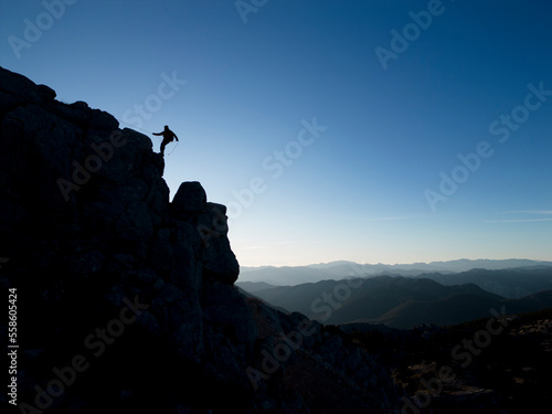 silhouette of mountaineer descending from cliff on cliff