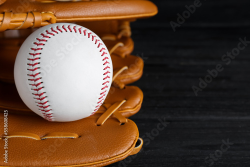 Catcher's mitt and baseball ball on black background, closeup with space for text. Sports game