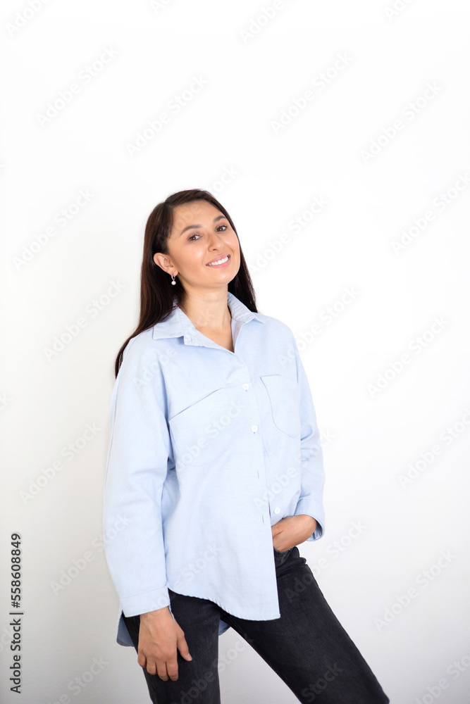 Portrait of a beautiful brunette woman in a blue shirt on a white background. Neutral makeup. Space for text Portrait of a beautiful brunette woman in a blue shirt on a white background. Neutral makeup. Space for text