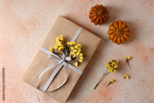 Fototapeta Naklejka Na Ścianę i Meble -  Pumpkin shaped candles and book decorated with flowers on beige textured background, flat lay