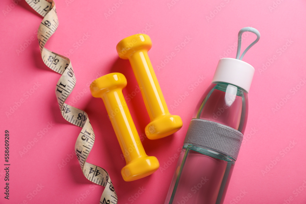 Measuring tape, bottle of water and dumbbells on pink background, flat lay. Weight control concept Measuring tape, bottle of water and dumbbells on pink background, flat lay. Weight control concept