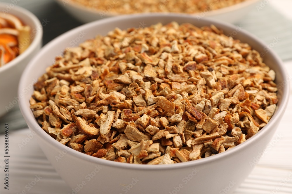Bowl with dried orange seasoning zest on white wooden table, closeup Bowl with dried orange seasoning zest on white wooden table, closeup