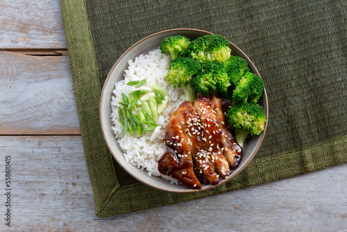 Healthy food teriyaki chicken has rice and vegetables in bowl on wood table.