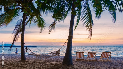 Fototapeta Naklejka Na Ścianę i Meble -  Hammock and beach chairs on the beach with palm trees during sunset at Na Jomtien Beach Pattaya Thailand.