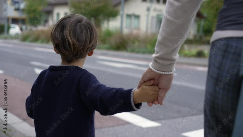 Child holding mother hands waiting to cross street at crosswalk. Family trust concept. Parent and kid hand held together Child holding mother hands waiting to cross street at crosswalk. Family trust concept. Parent and kid hand held together