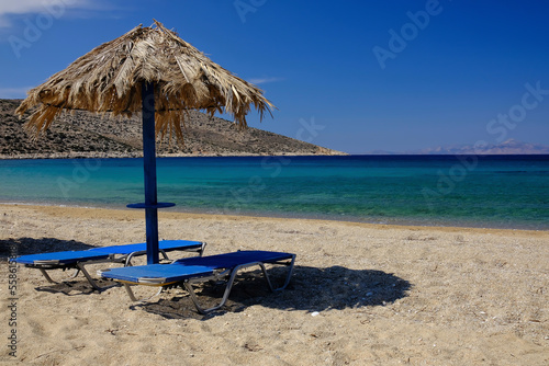 Two sun beds and a sun umbrella at the amazing beach of Agia Theodoti in Ios Greece © DIMITRIOS