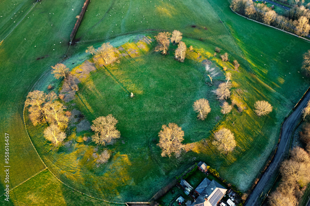 Mayburgh Henge prehistoric monument at Eamont Bridge, Cumbria, showing massive circular embankment and remaining central megalith. Aerial winter