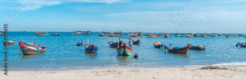 Panorama white sandy beach  calm waves with traditional wooden fishing boat anchored near shoreline in sunny cloud blue sky at Bai Truoc  Vung Tau  Vietnam