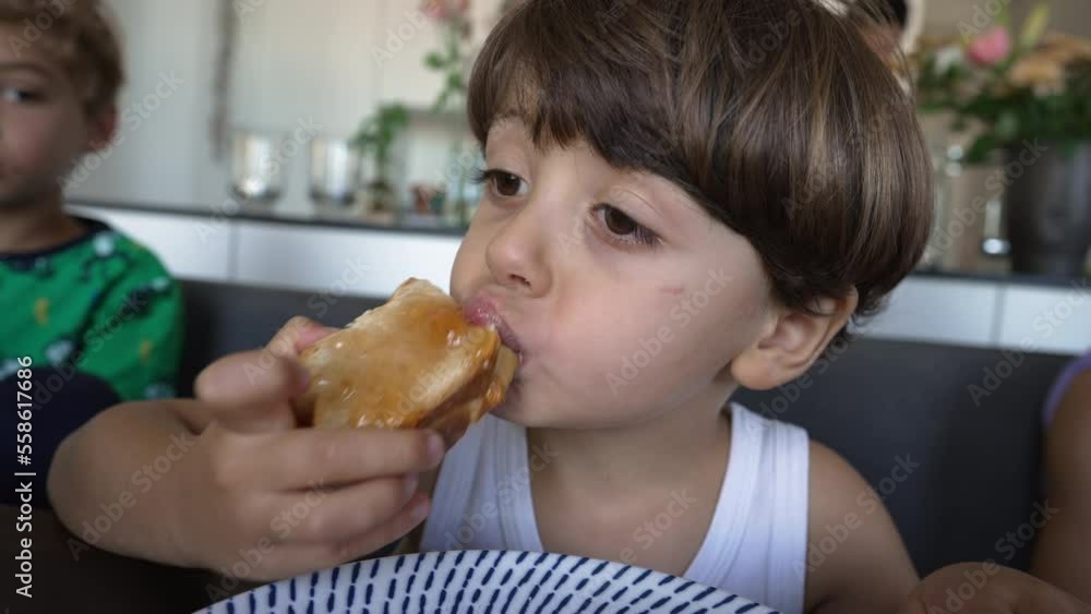 Child eating breakfast in the morning. One small boy eats bread with jelly portrait face close up Child eating breakfast in the morning. One small boy eats bread with jelly portrait face close up