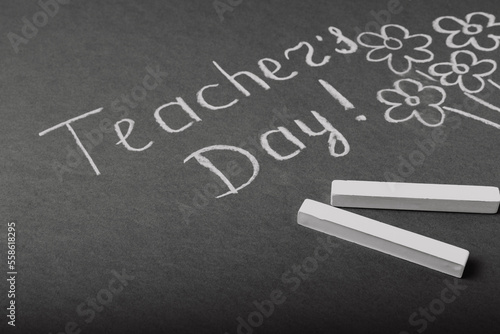 Chalk lettering TEACHER'S DAY and a bouquet of flowers on a black chalkboard. Concept Teacher's Day.