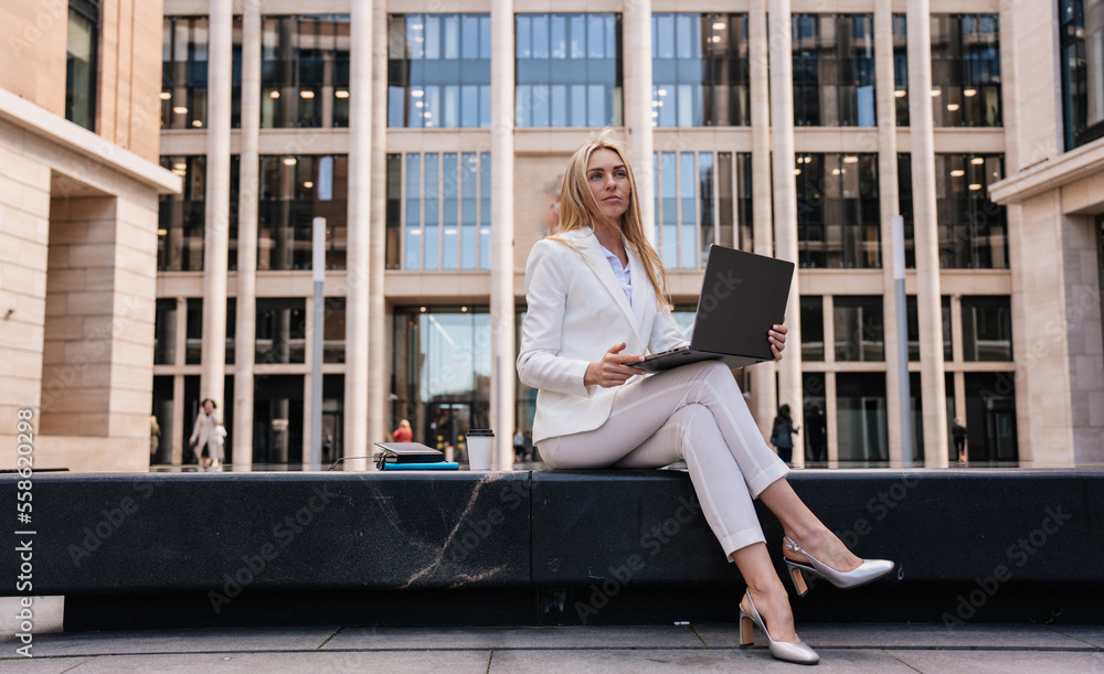 © Iona - Upset young blonde entrepreneur woman using laptop with sad facial expression sitting outdoors against large building. Pretty student girl preparing for exam. Overloaded businesswoman typing letter. © Iona - Upset young blonde entrepreneur woman using laptop with sad facial expression sitting outdoors against large building. Pretty student girl preparing for exam. Overloaded businesswoman typing letter.