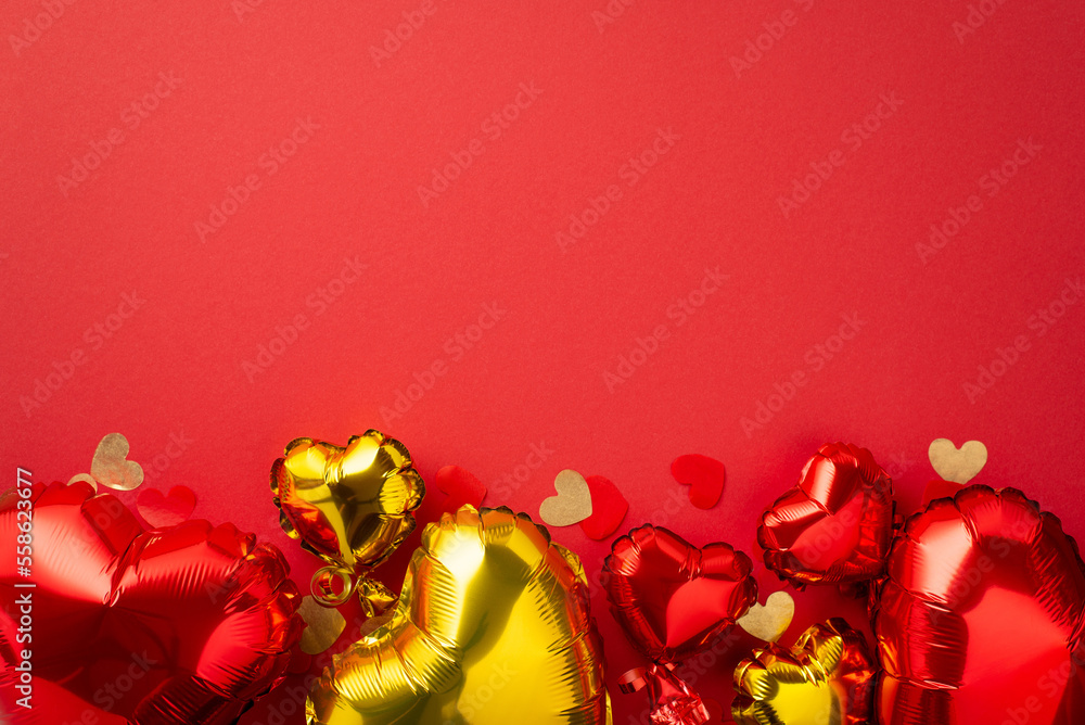 Valentine's Day decorations concept. Top view photo of heart shaped red yellow balloons and confetti on isolated red background with empty space