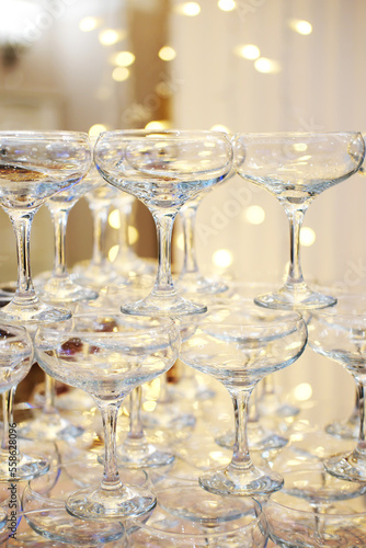 Pyramid of empty champagne glasses against golden bokeh background