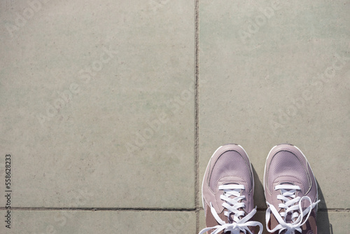 pink new sneakers stand on gray paving stones. Place for text. View from above