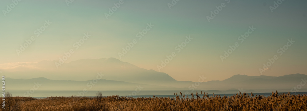 Banner panorama of Lake Beysehir in Turkey and mountains in light fog.