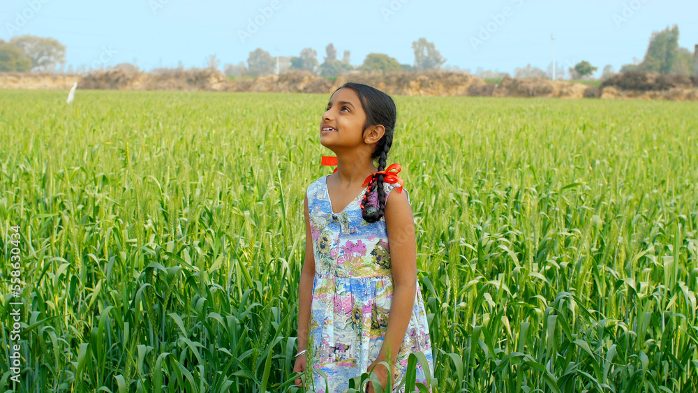 An Indian girl standing in a field breathing the fresh air and enjoying ...