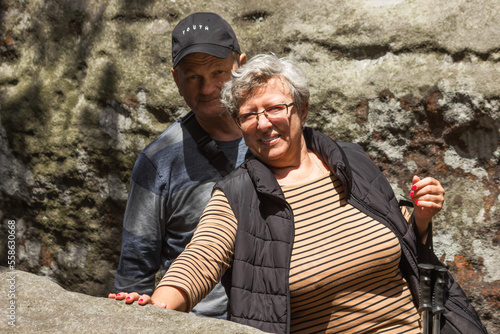 Happy senior couple tourists hiking on top of mountain between stones and rocks. Active seniors concept. Healthy life.